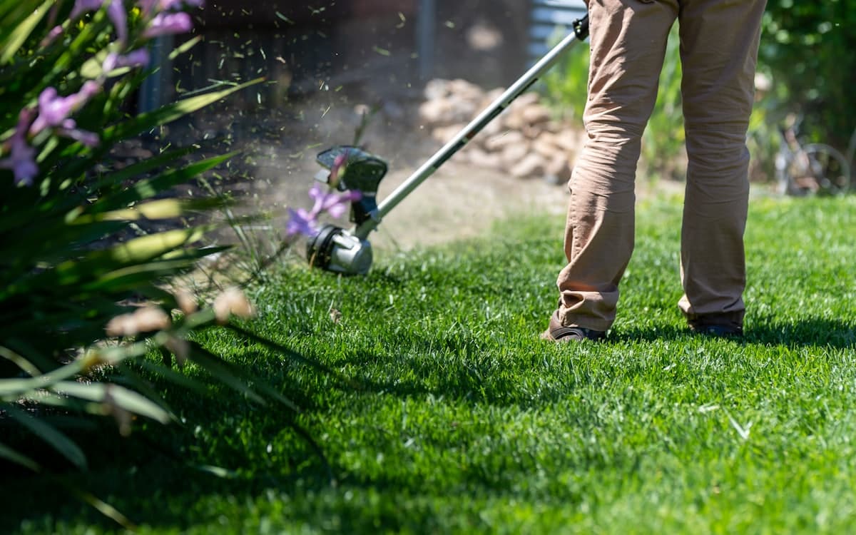 A landscaper edging a lawn with a line trimmer