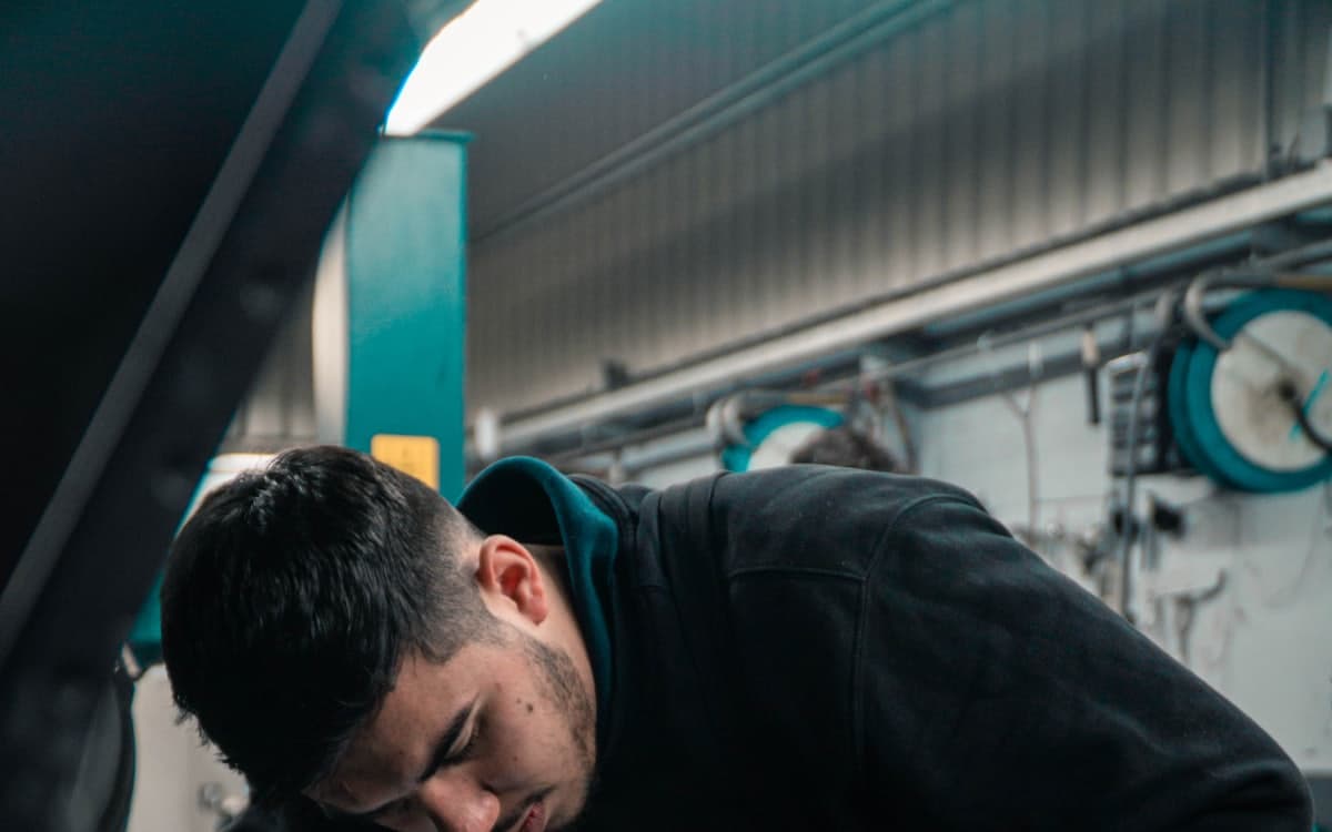 A mechanic working under a raised car in a workshop